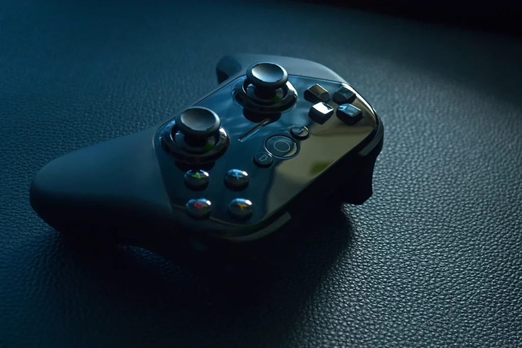 Close-up of a gaming controller with a blog page visible on a screen in the background