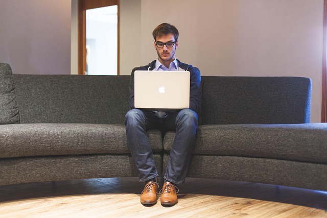 A man sitting on a couch using a laptop