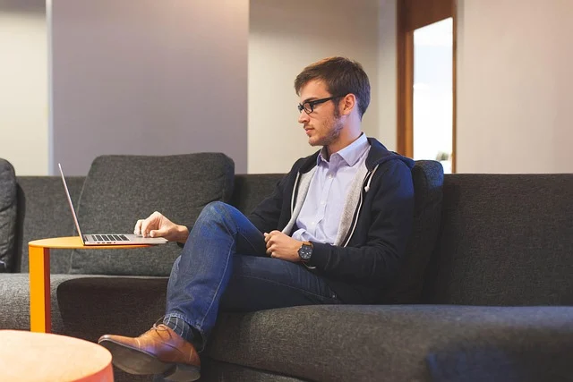 A young man sitting on a couch using a laptop