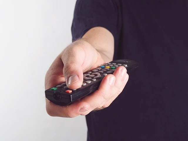 Conditional access system: A hand holding a television remote control pointed forward