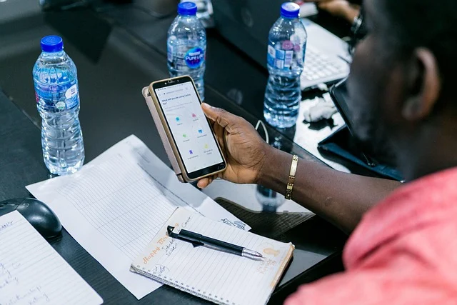 Ai updates: A person using a smartphone at a desk with water bottles and notebooks.
