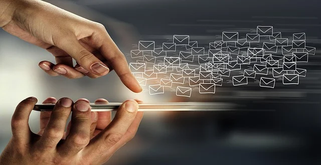 Hands interacting with a phone, sending multiple email icons.