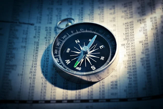 A compass on top of a financial newspaper with market data.