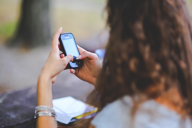A woman holding and typing on a smartphone outdoors