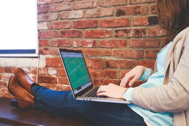 A woman sitting with her feet up typing on a laptop