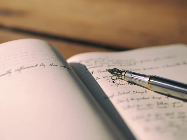 A fountain pen resting on an open notebook with handwritten notes.