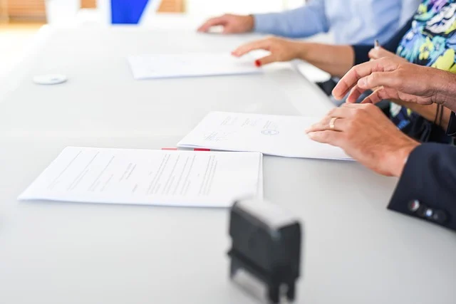 Doubtnut valuation: People sitting at a table with contract documents for a deal