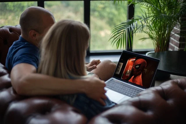 A couple watching a movie on a laptop, Spiderman on screen