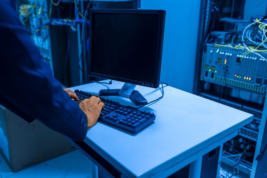 A person typing on a computer keyboard in a server room