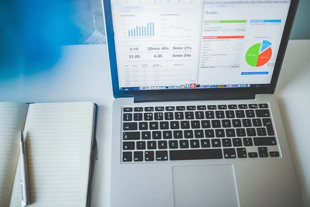 Technewsoutlets. com: Laptop displaying charts and data, with a notebook and pen beside it.