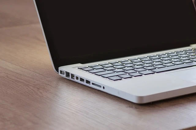 A laptop with a blank screen on a wooden desk.