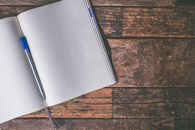 An open blank notebook with a pen on a wooden surface