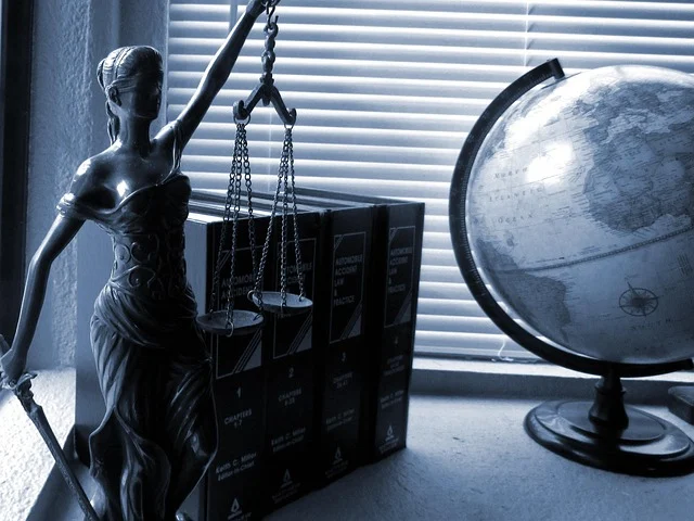 Lady Justice statue, law books, and a globe on a desk
