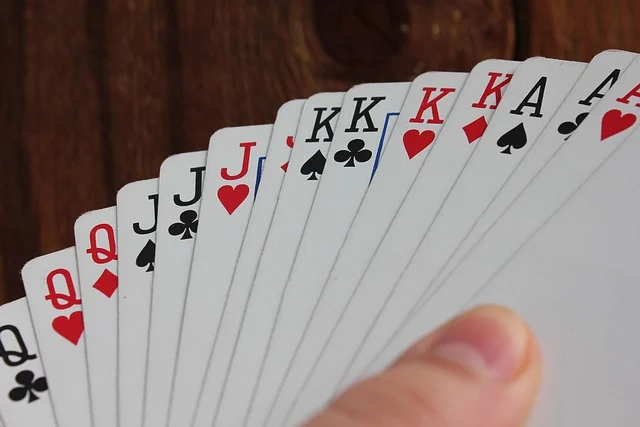 A hand holding a fan of playing cards, showing various suits and ranks.
