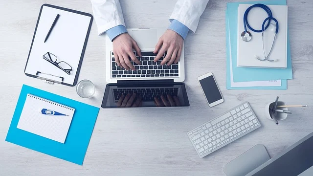 A doctor or medical professional working on a laptop with medical tools.