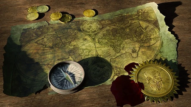 An old map, compass, coins, and a skull medallion on a wooden table.