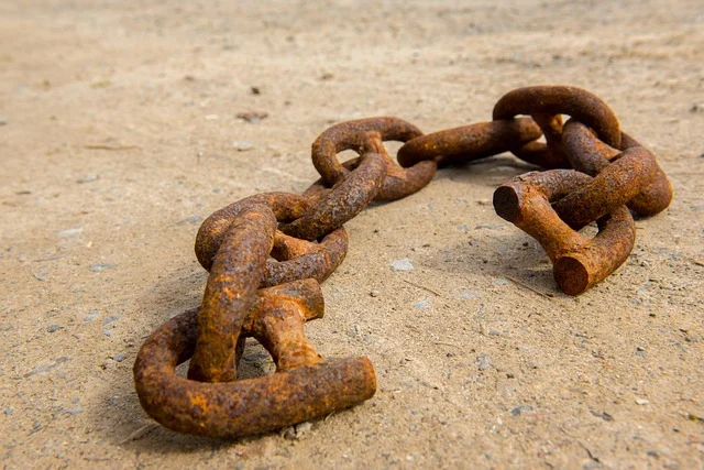 A rusty, broken chain lying on the ground, symbolizing a broken link.